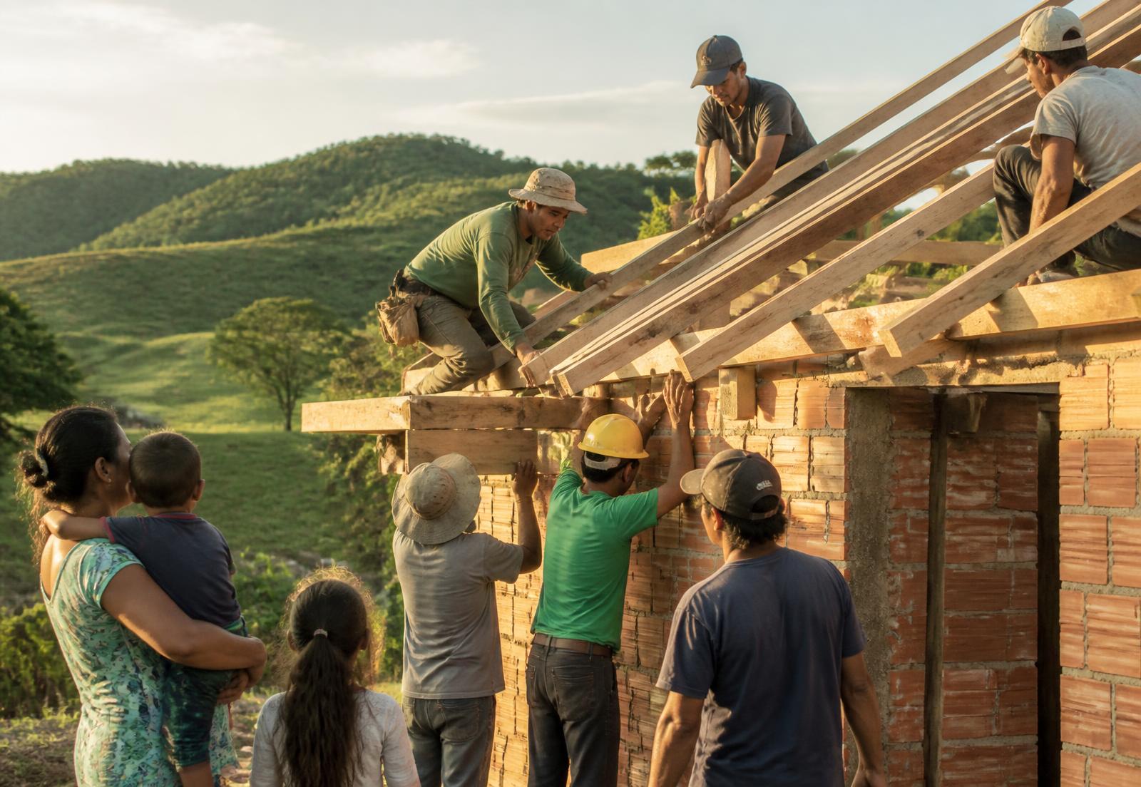 Voluntários e moradores erguendo o telhado de uma casa reconstruída no Rio Grande do Sul